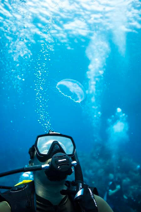 diver in warm blue water looking up at his bubbles