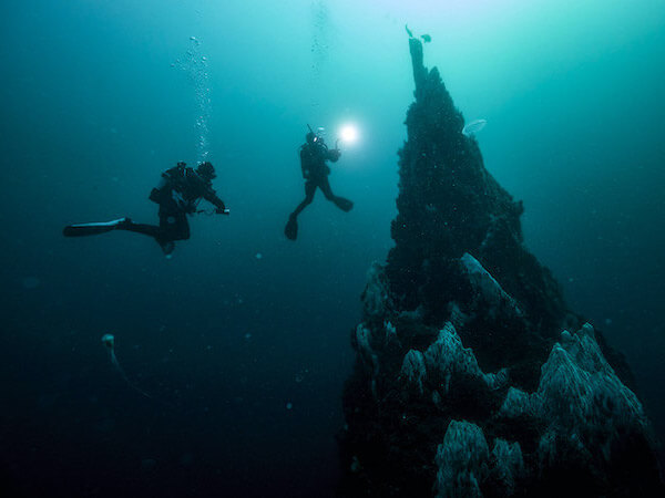 Divers exploring a pinnacle during a deep dive.